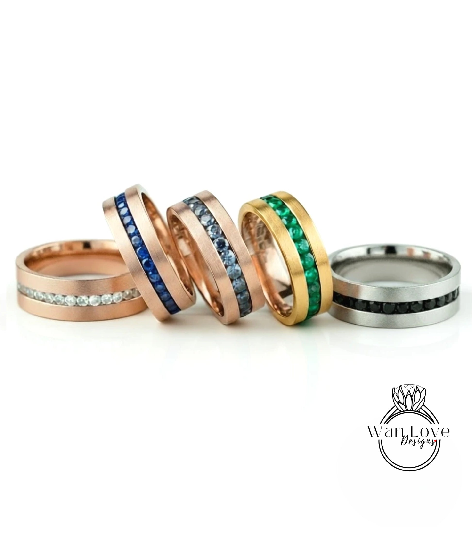 a collection of five rings with various gemstone bands, arranged in a row on a white background.