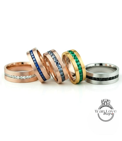 a collection of five rings with various gemstone bands, arranged in a row on a white background.