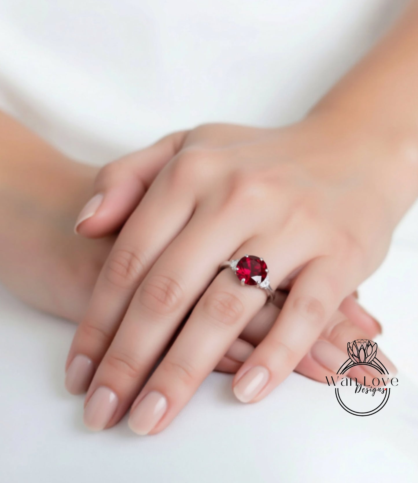 A close-up image of a person's hand wearing a ring with a large red gemstone.