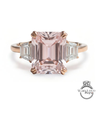 A pink gemstone engagement ring with a large central gemstone surrounded by smaller gemstones on either side.