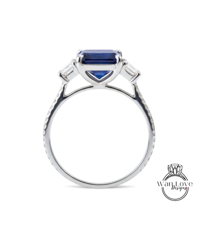 A silver engagement ring with a large blue gemstone, possibly a sapphire, set in a three-pronged diamond design.