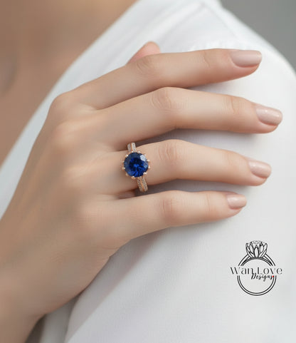 A close-up of a person's hand wearing a gold ring with a large blue gemstone.