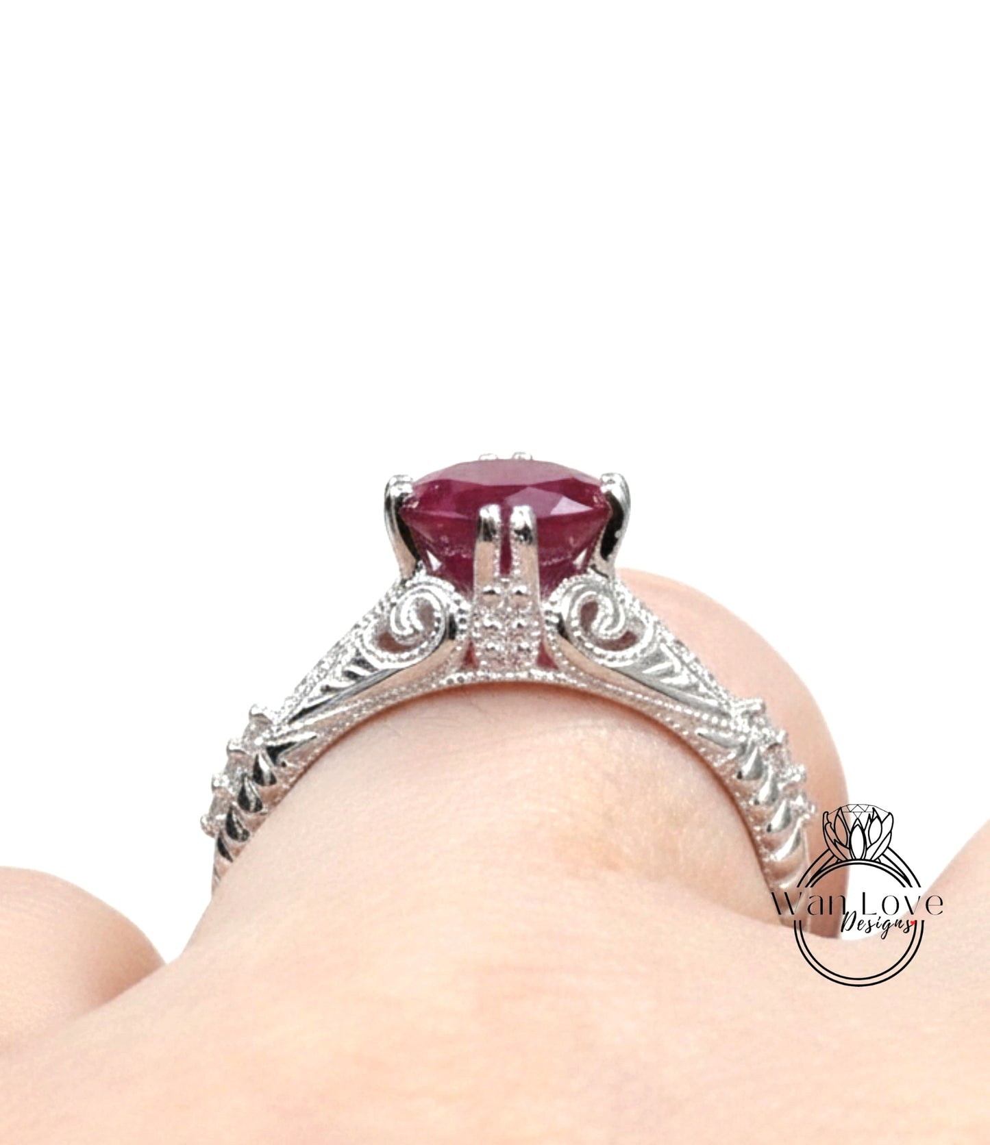 A close-up view of a silver ring with a large, deep red gemstone, possibly a ruby, set in an ornate, decorative design.