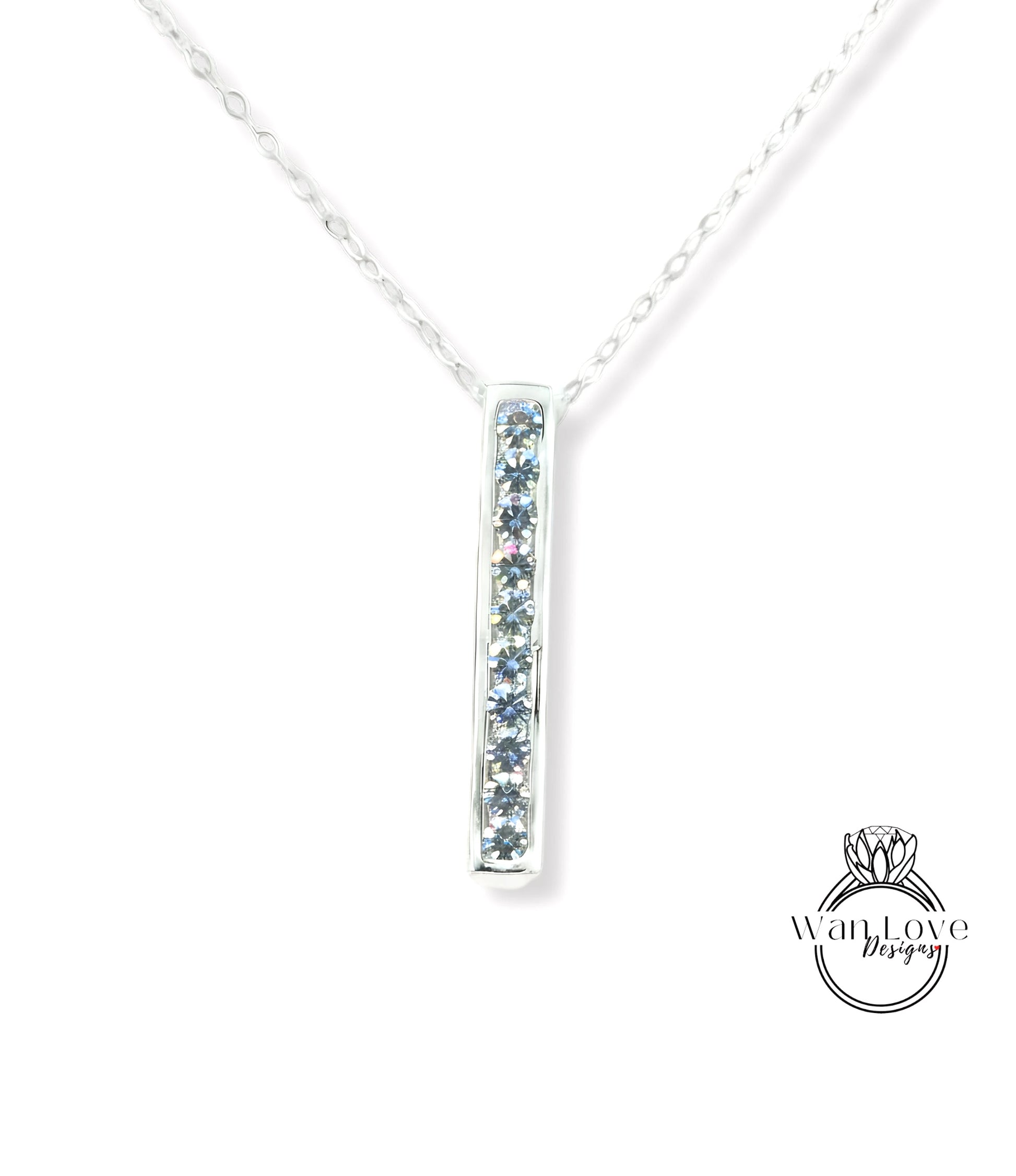 A silver necklace with a pendant featuring a row of blue gemstones.