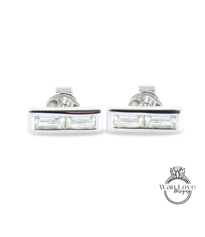 A pair of silver earrings with rectangular cut gemstones.