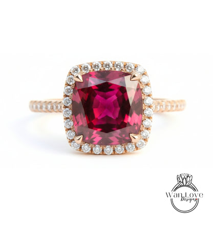 A large, deep red gemstone set in a gold ring with a halo of smaller diamonds around the edge.
