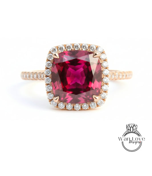 A large, deep red gemstone set in a gold ring with a halo of smaller diamonds around the edge.