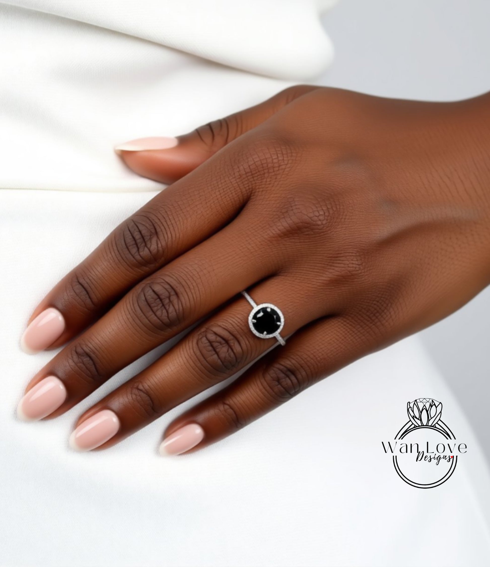 A close-up of a hand wearing a ring with a black gemstone, resting on a white surface.