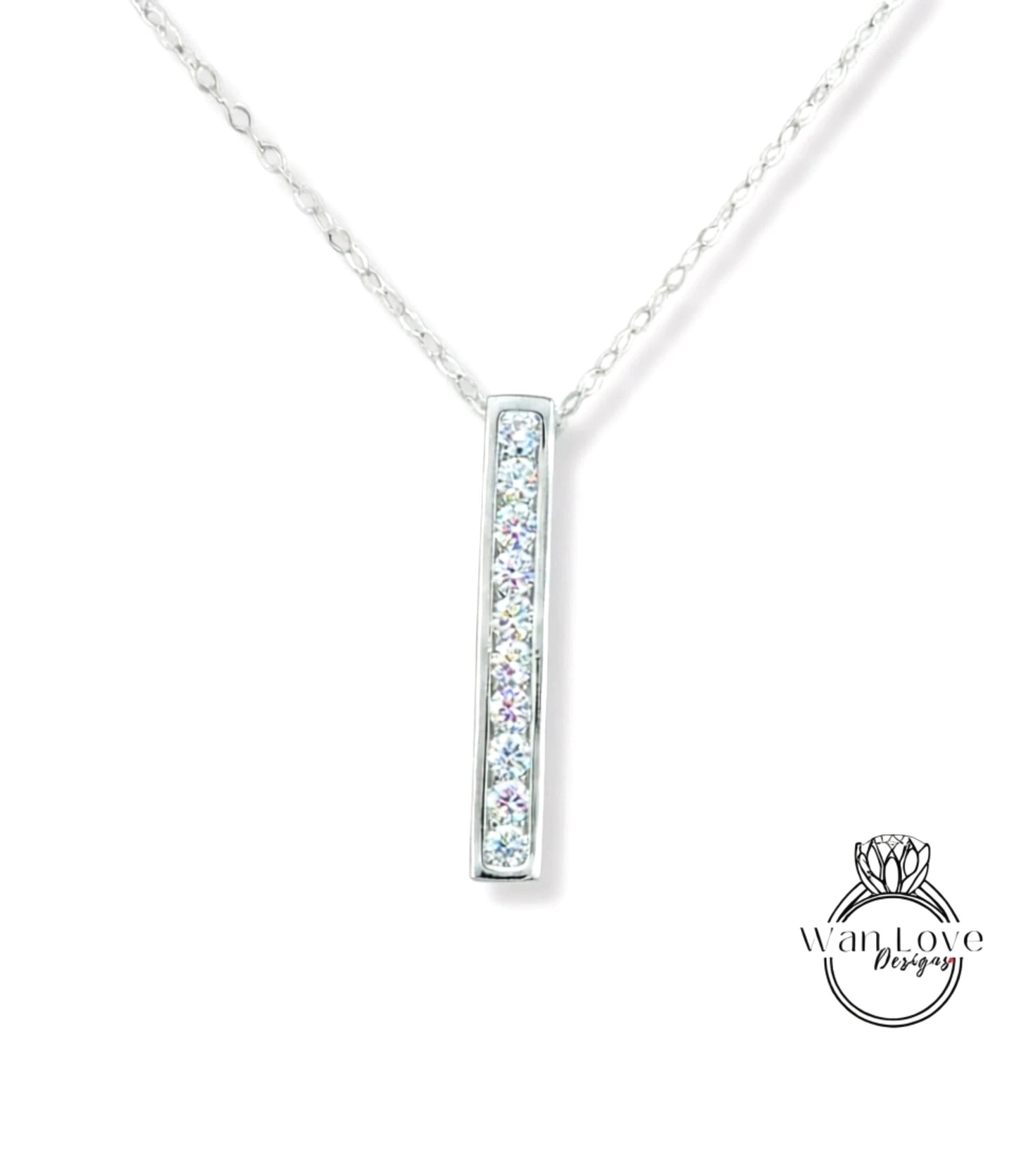 A silver necklace with a rectangular pendant featuring a row of small diamonds.