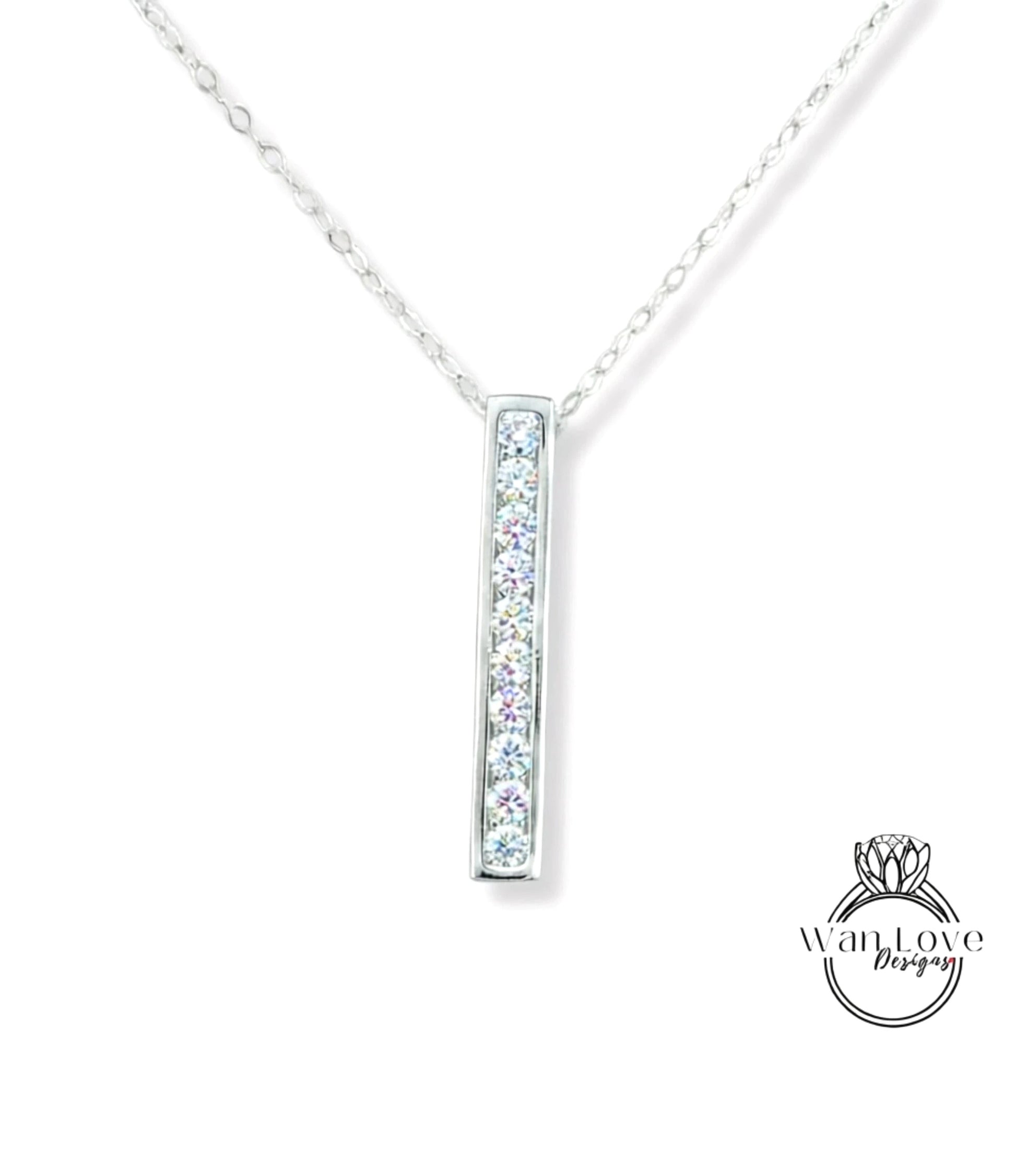 A silver necklace with a rectangular pendant featuring a row of small diamonds.