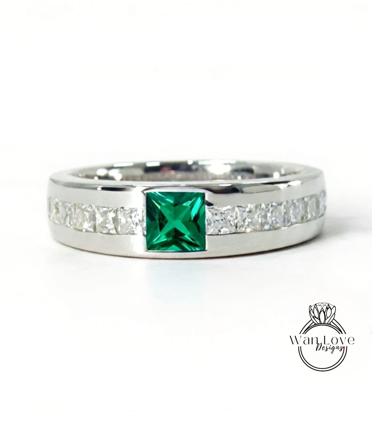 A silver ring with a large green gemstone in the center, surrounded by smaller diamonds along the band.