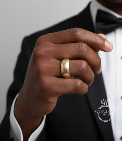 A close-up of a person's hand wearing a gold ring, with a black suit jacket visible.