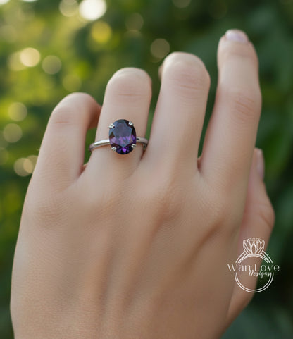 A close-up of a hand wearing a ring with a large purple gemstone, set in a silver band.