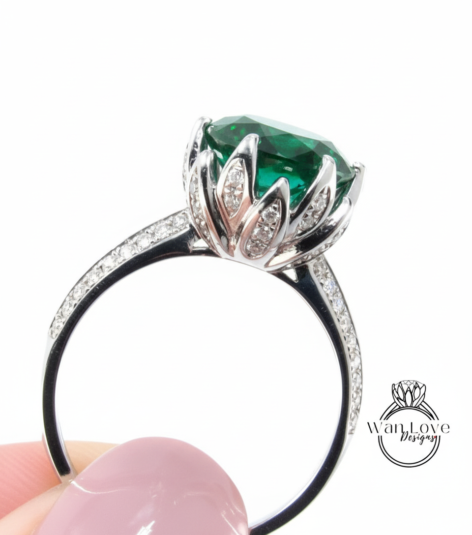 A close-up of a silver ring with a large, green gemstone, possibly a diamond, set in a floral-designed band.