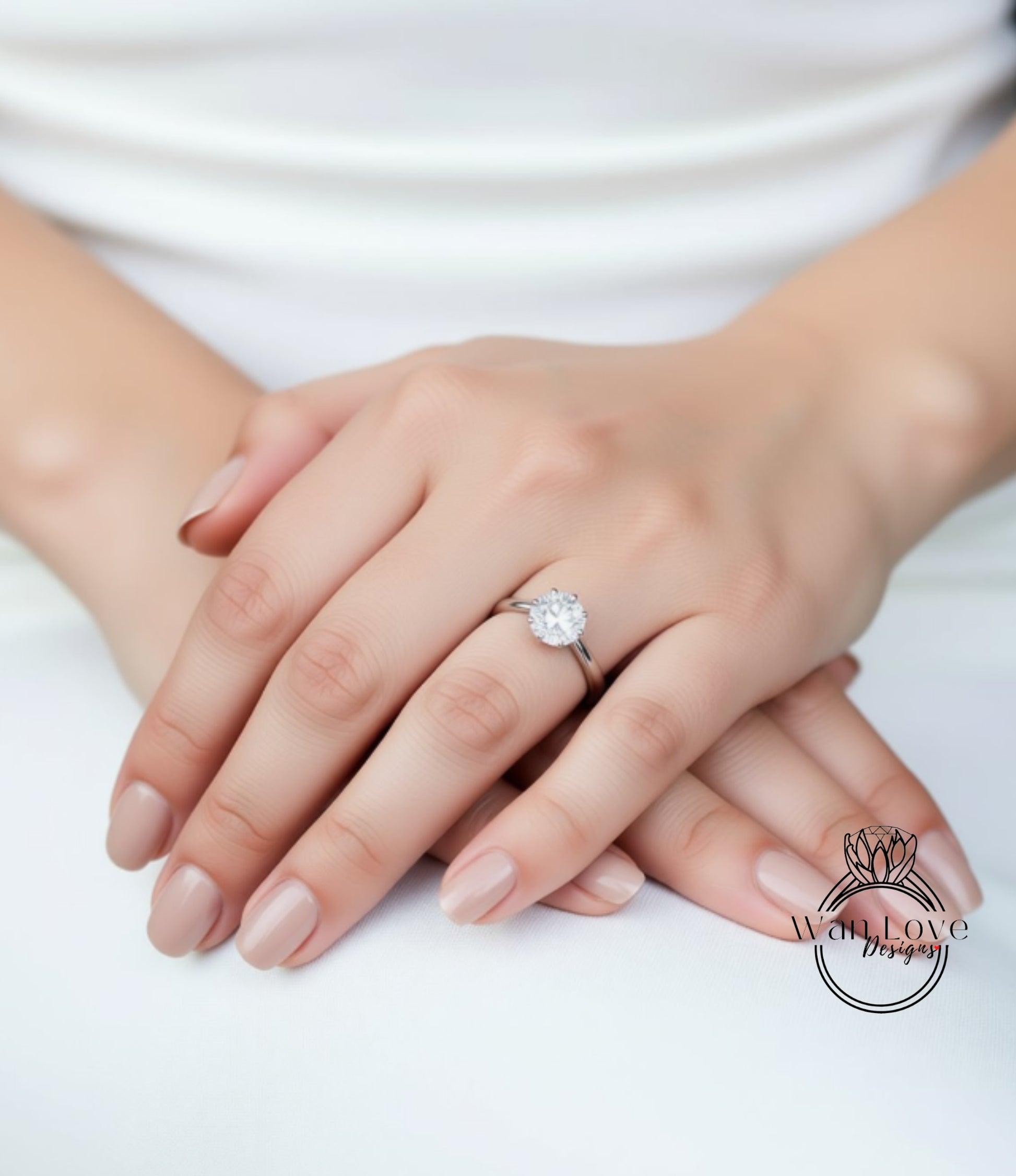 A close-up of a person's hands with a diamond engagement ring on the ring finger.