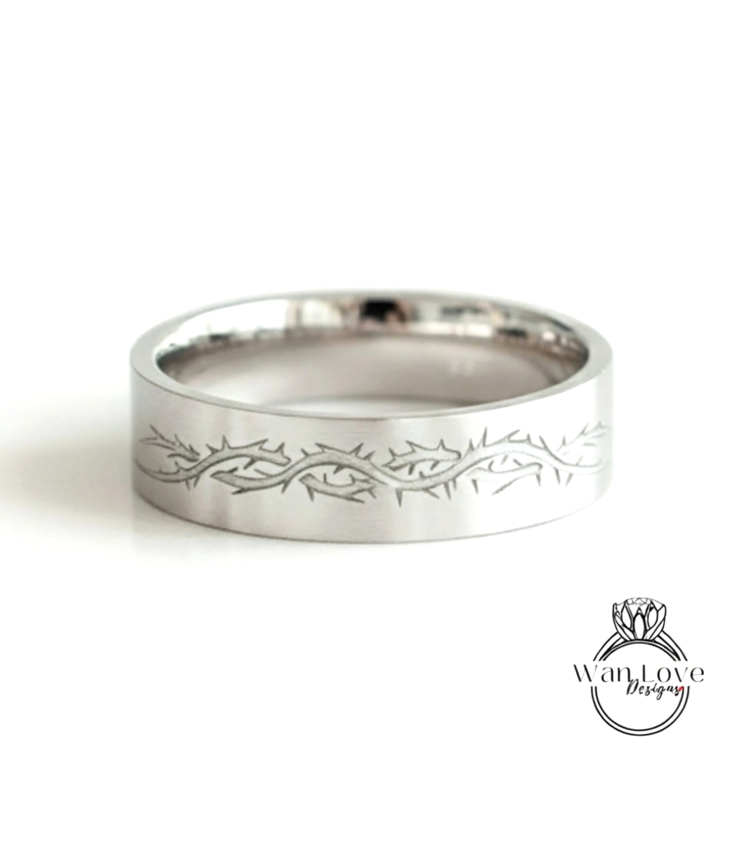 A silver ring with a decorative design featuring a thorny pattern.