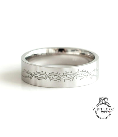 A silver ring with a decorative design featuring a thorny pattern.