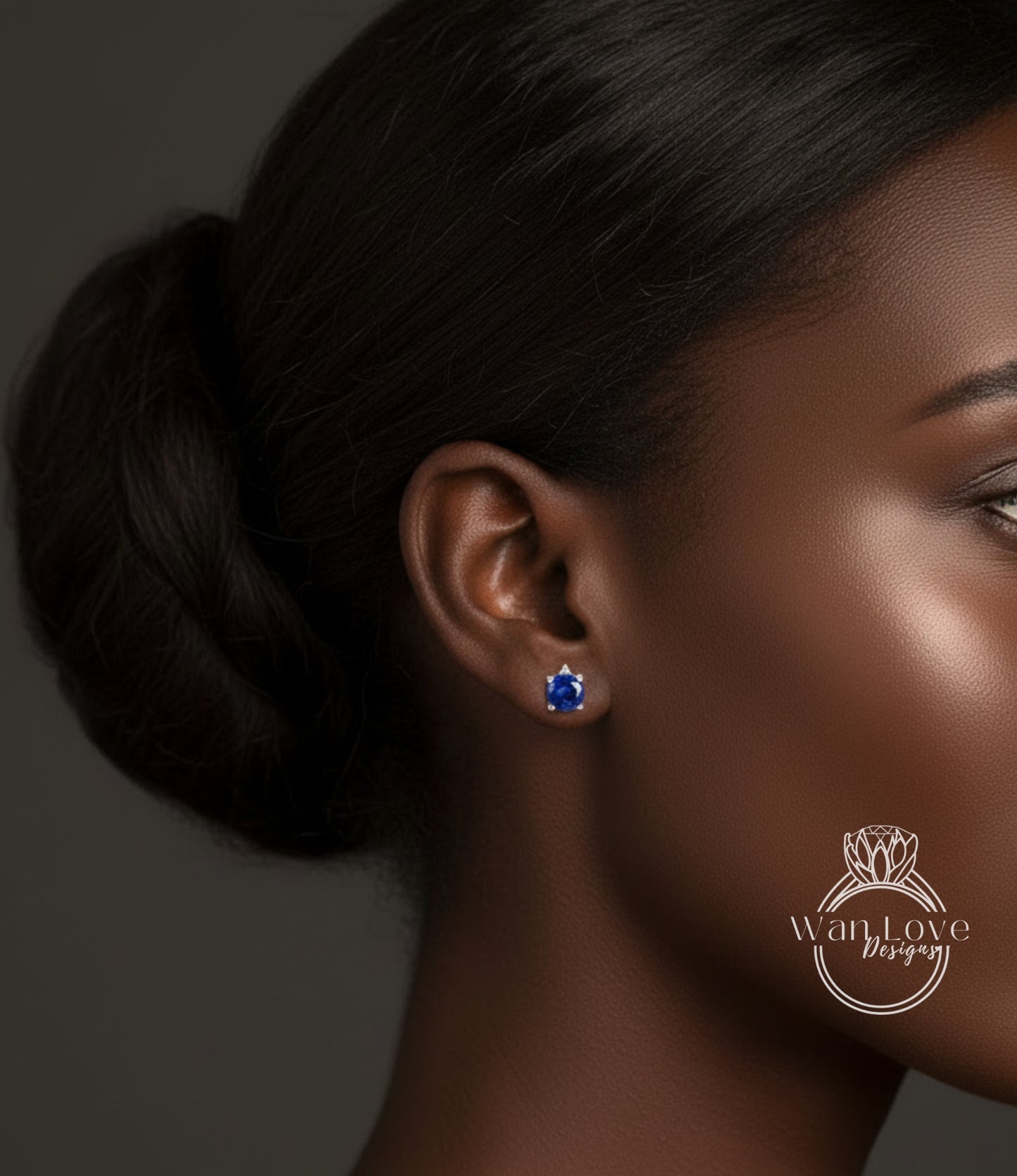 A close-up of a woman's face, focusing on her earrings with a blue gemstone.