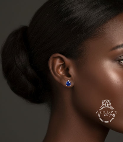 A close-up of a woman's face, focusing on her earrings with a blue gemstone.