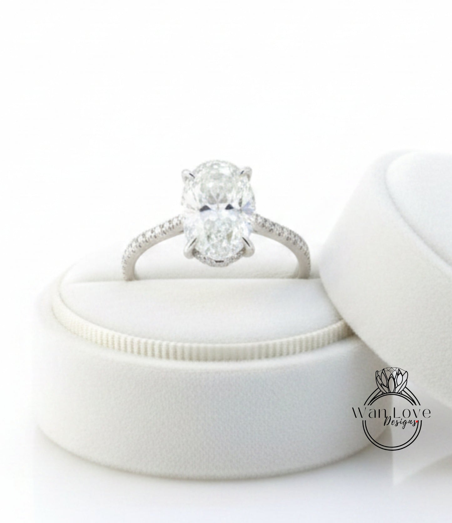 A diamond engagement ring is displayed on a white velvet cushion, showcasing the ring's intricate details and sparkling diamond.