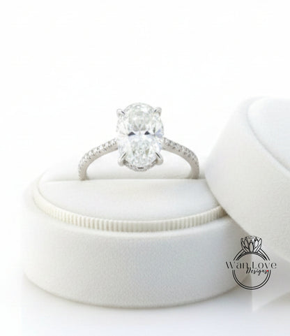 A diamond engagement ring is displayed on a white velvet cushion, showcasing the ring's intricate details and sparkling diamond.