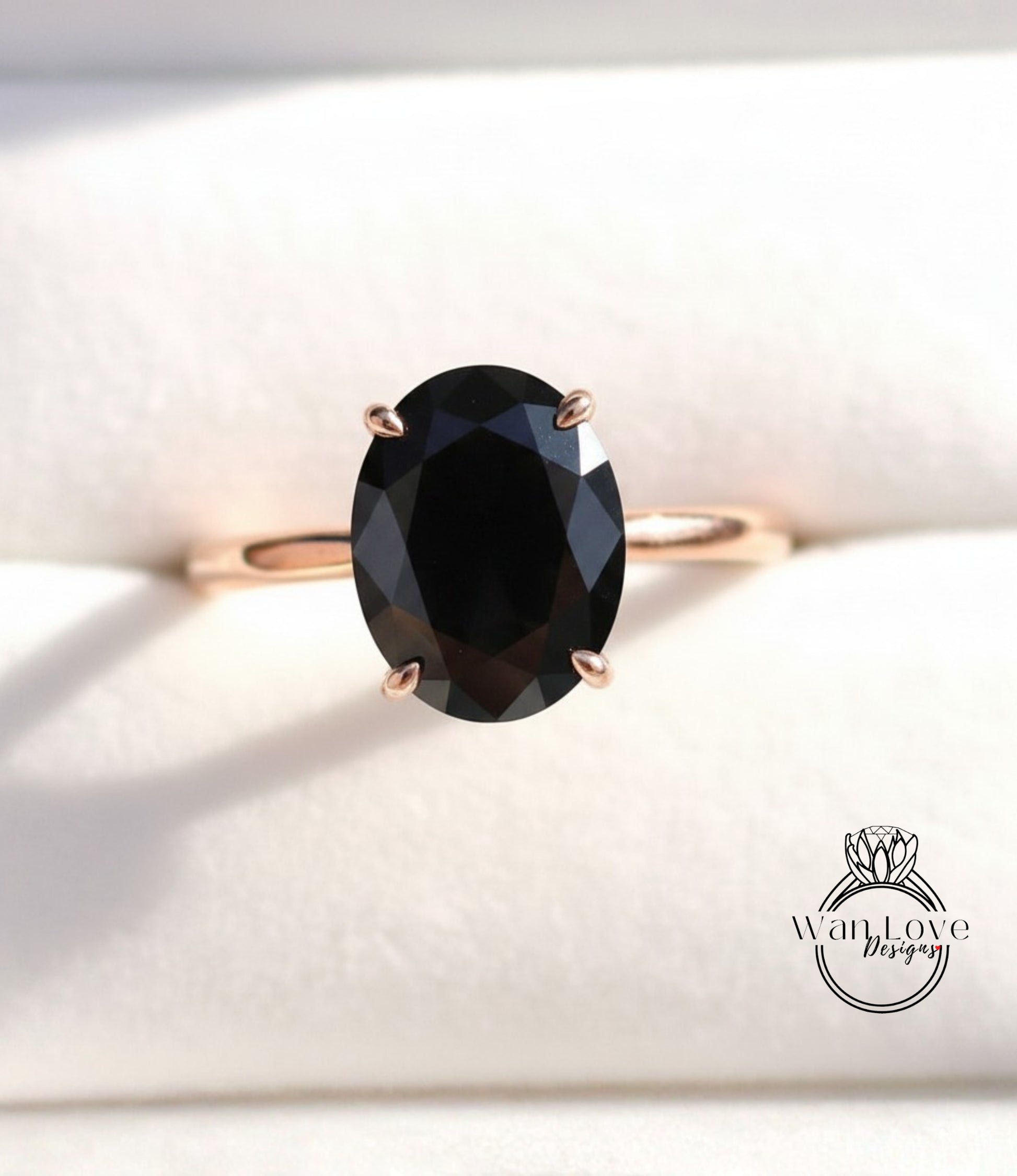 A close-up image of a gold ring with a large oval-shaped black gemstone, placed on a white background.