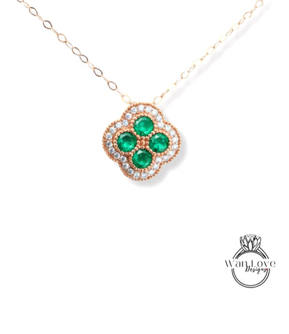 A necklace with a pendant featuring a cluster of green gemstones, likely emeralds, surrounded by a decorative design.