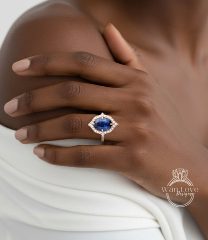 A close-up of a person's hand wearing a ring with a large blue gemstone, resting on a white fabric.