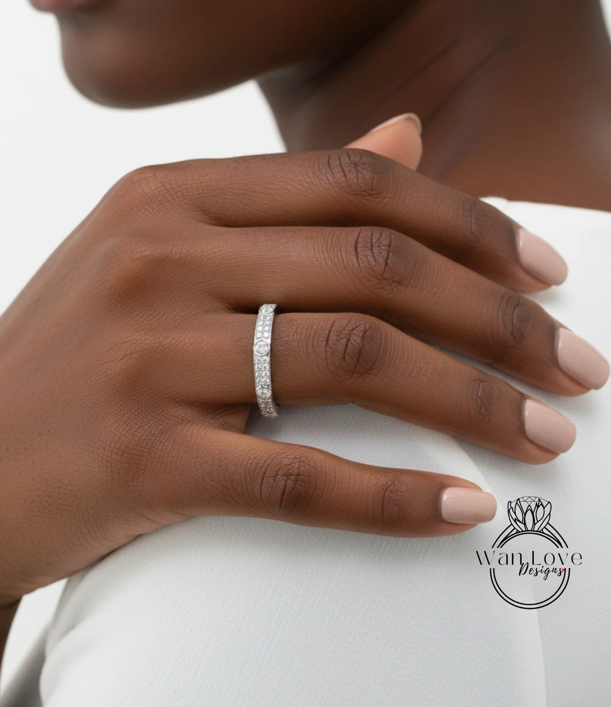 A close-up of a person's hand wearing a diamond ring on the ring finger.