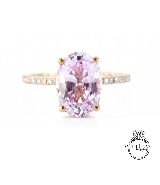 A pink gemstone engagement ring with a gold band and small diamonds.