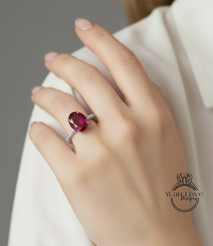A close-up of a hand wearing a ring with a large, deep red gemstone.