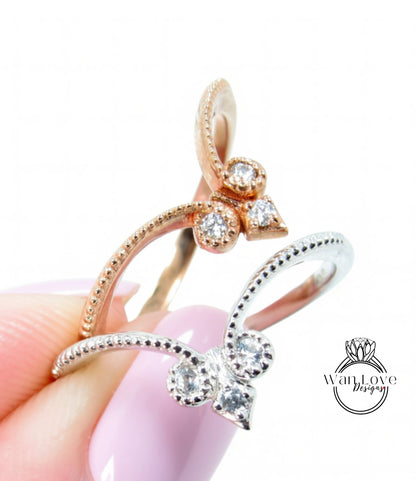 A close-up image of a person's hand holding a ring with a floral design and small diamonds.