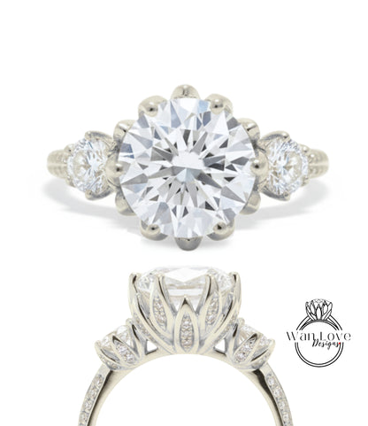 A stunning diamond engagement ring with a large central diamond surrounded by smaller diamonds on either side, set in a silver band with a scalloped edge.