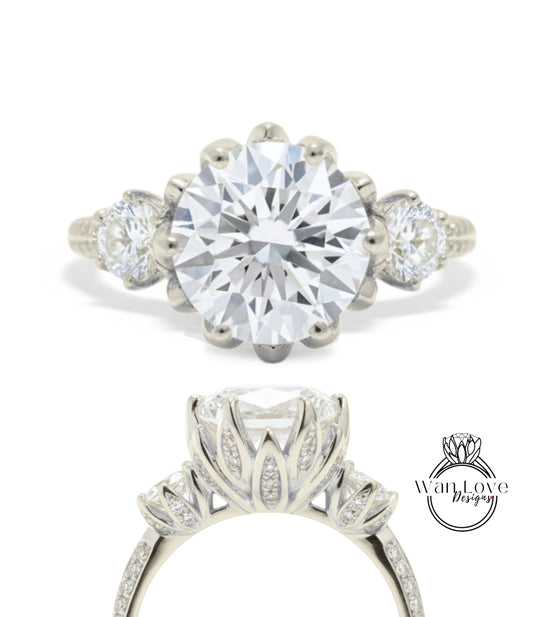 A stunning diamond engagement ring with a large central diamond surrounded by smaller diamonds on either side, set in a silver band with a scalloped edge.