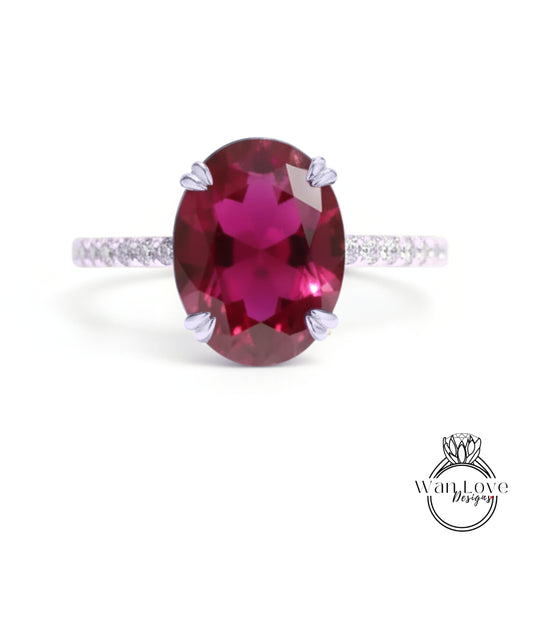 A large, oval-shaped, deep red gemstone, possibly a garnet, set in a silver ring with a thin band.