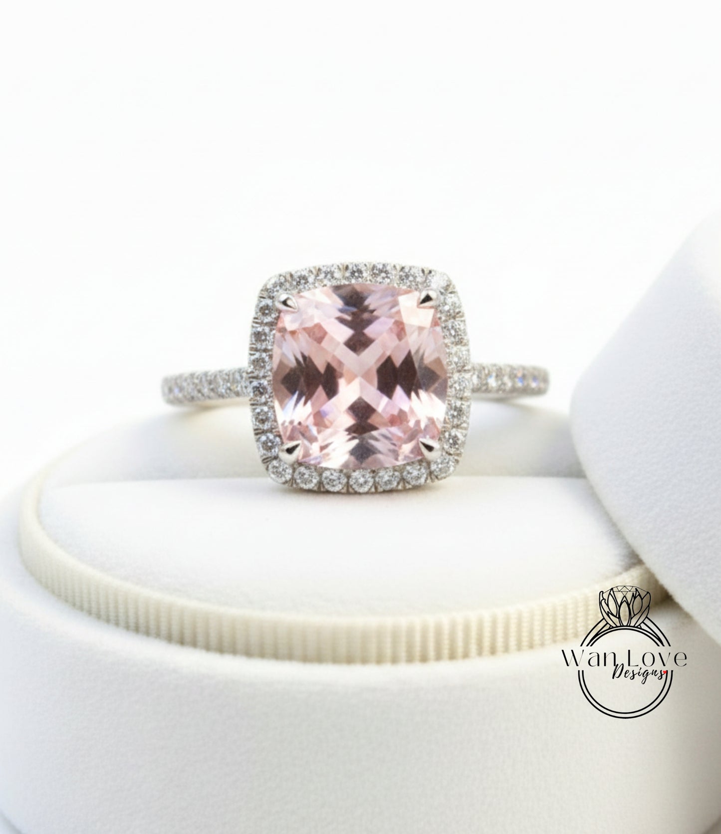 A large, pink gemstone ring with a halo of smaller diamonds around the center stone, displayed on a white surface.
