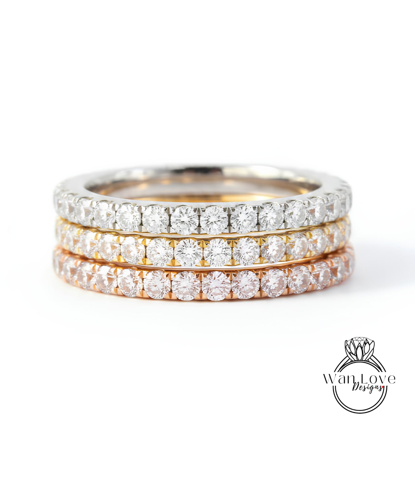 A close-up image of a three-band diamond ring with a gradient of colors, including silver, gold, and orange.