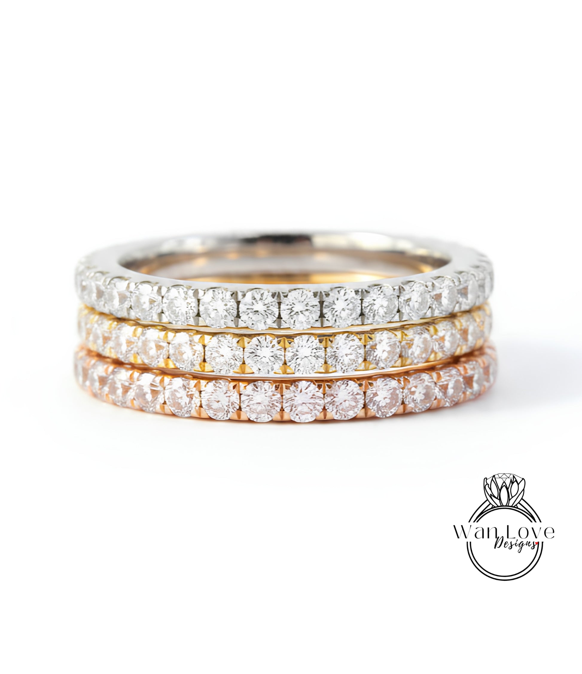 A close-up image of a three-band diamond ring with a gradient of colors, including silver, gold, and orange.