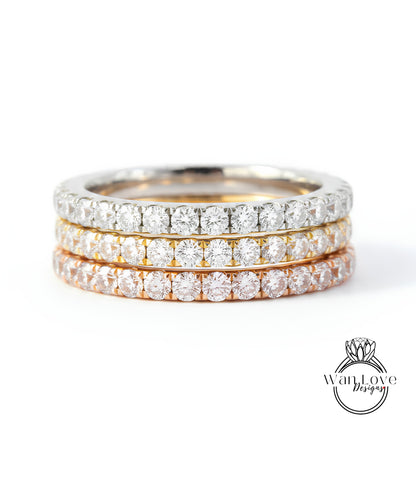 A close-up image of a three-band diamond ring with a gradient of colors, including silver, gold, and orange.
