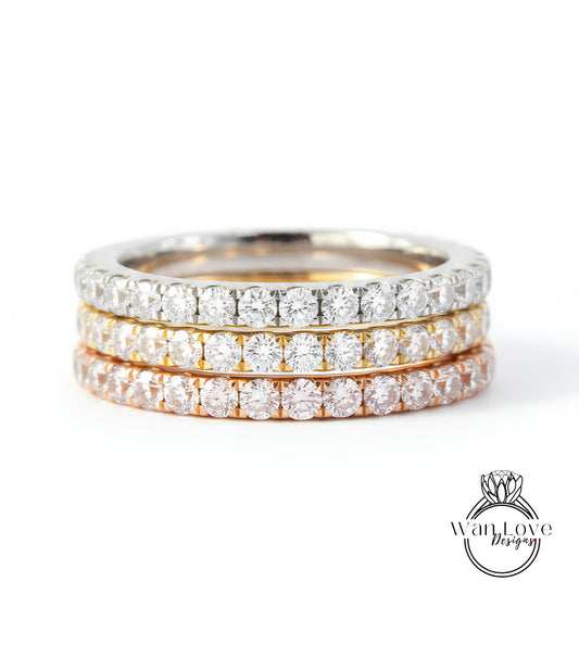 A close-up image of a three-band diamond ring with a gradient of colors, including silver, gold, and orange.