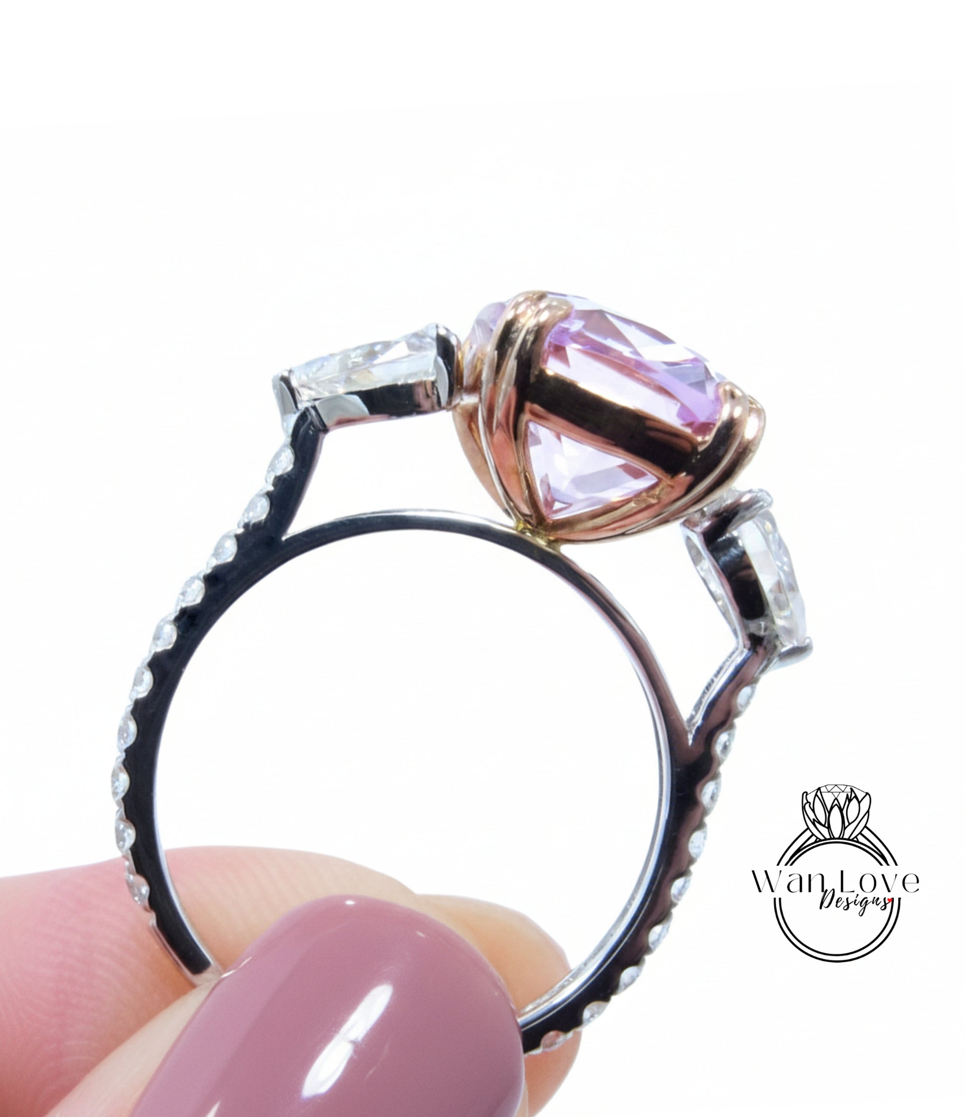 A close-up image of a person's hand holding a ring with a large pink gemstone, possibly a diamond, on top of it.