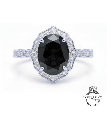 A silver ring with a large oval-shaped black gemstone at the center, surrounded by smaller diamonds.