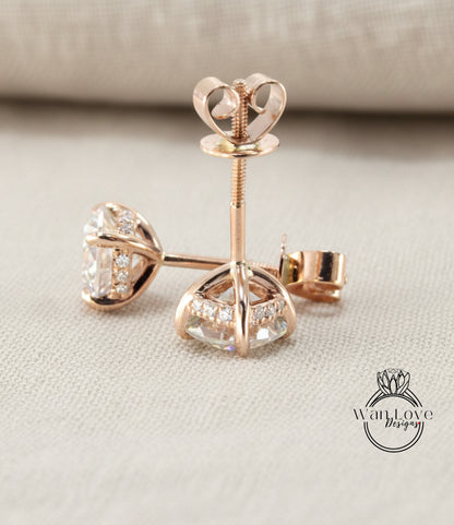 A pair of elegant gold earrings with clear gemstones, resting on a beige fabric background.