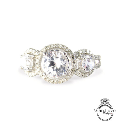 A close-up image of a diamond engagement ring with a large central diamond surrounded by smaller diamonds on the outer ring.