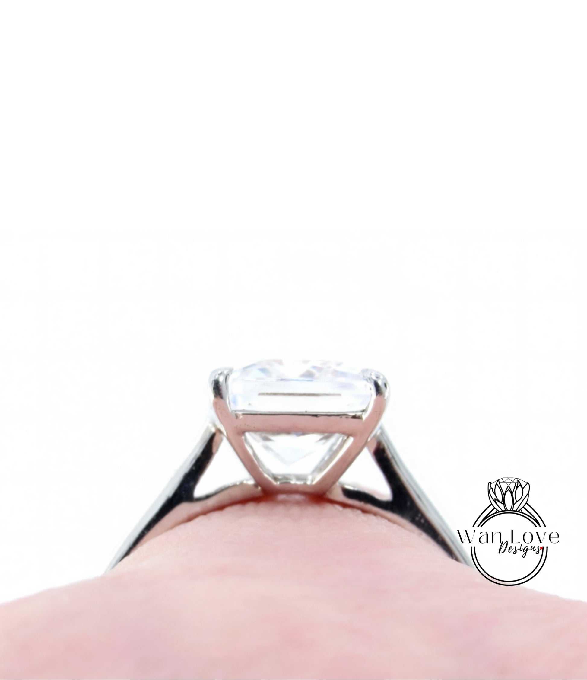 A close-up view of a diamond engagement ring on a person's finger, with a blurred background.