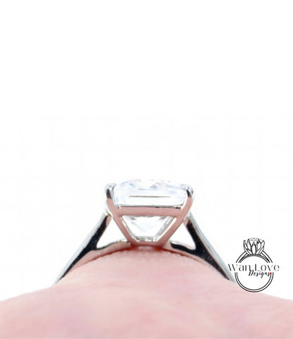 A close-up view of a diamond engagement ring on a person's finger, with a blurred background.