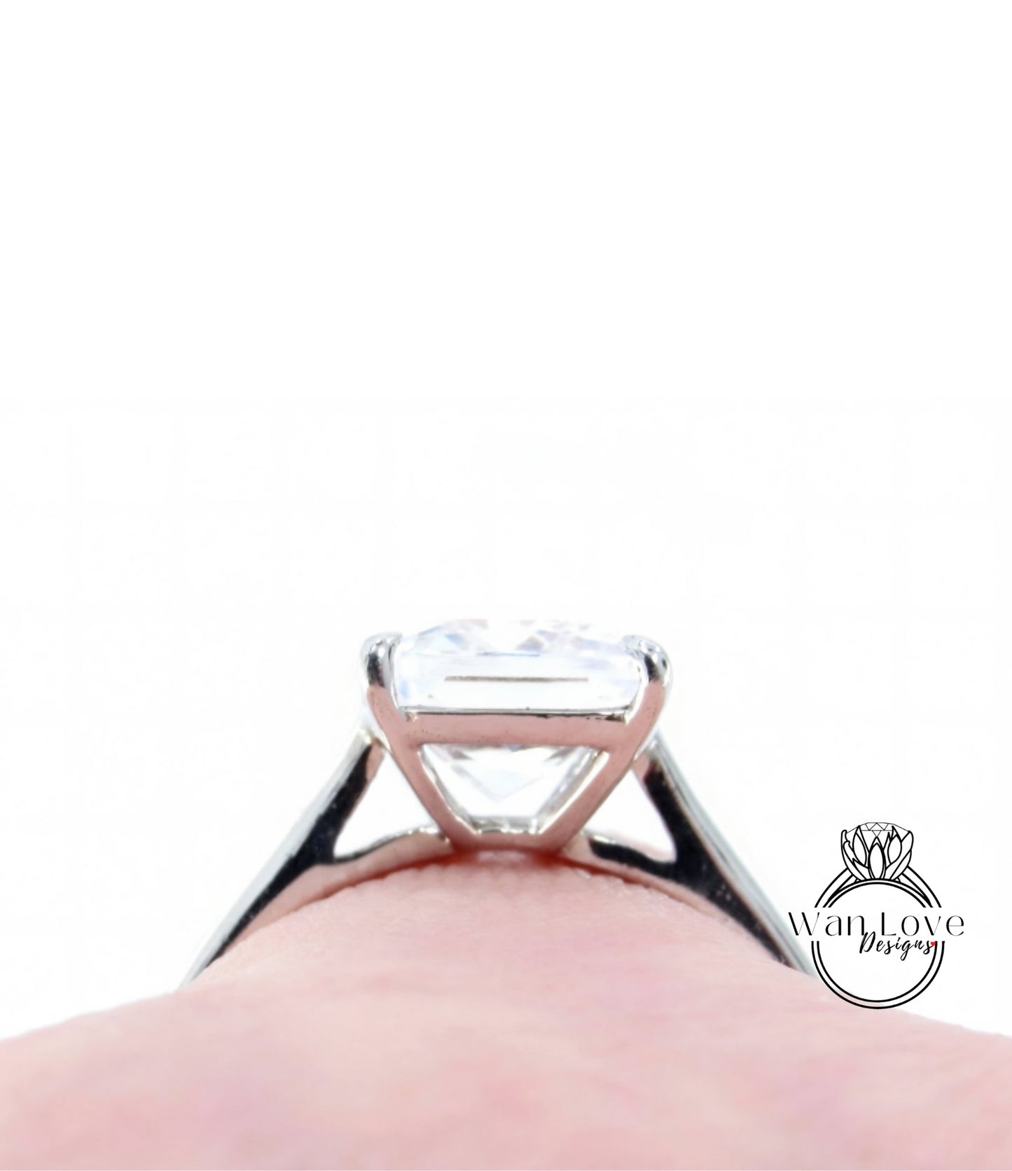 A close-up view of a diamond engagement ring on a person's finger, with a blurred background.