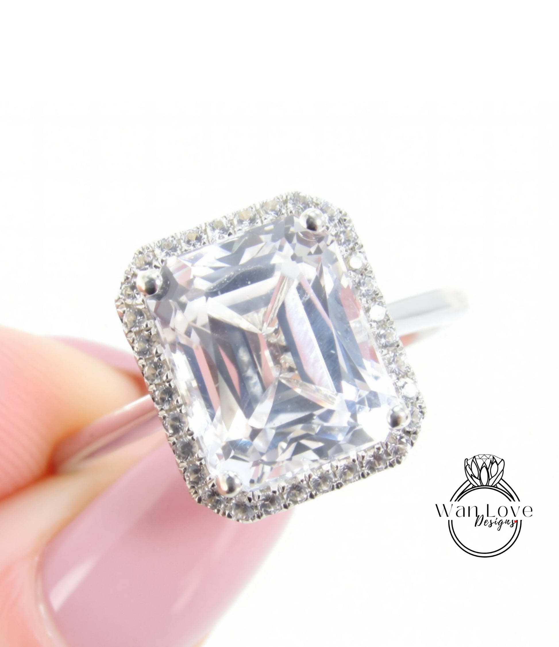A close-up image of a person's hand holding a diamond ring with a large, clear gemstone set in a halo of smaller diamonds.