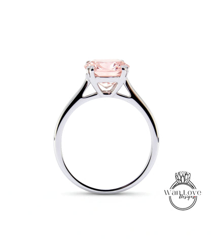 A silver engagement ring with a large pink gemstone set in the center.