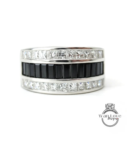 A silver ring with a black band and a row of diamonds set in it.